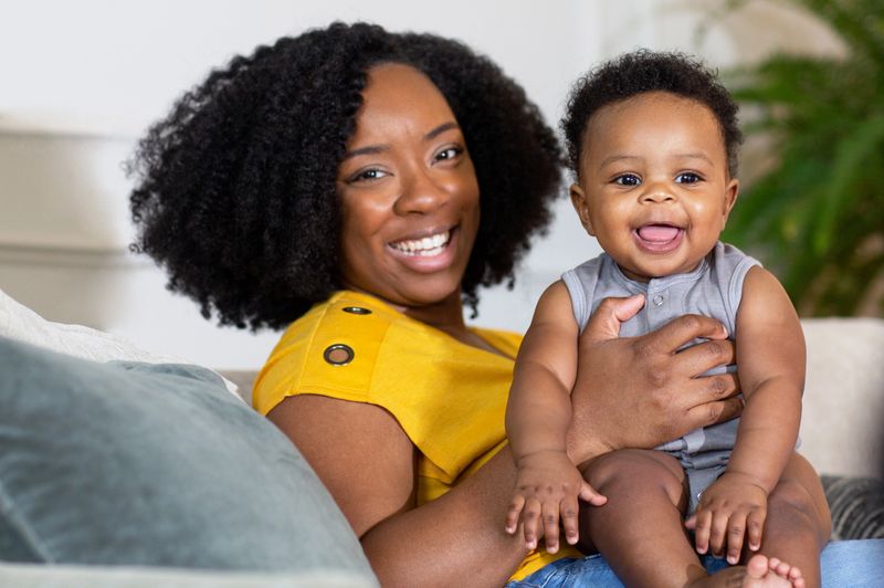 Young mother smiling and playing with her son at home.