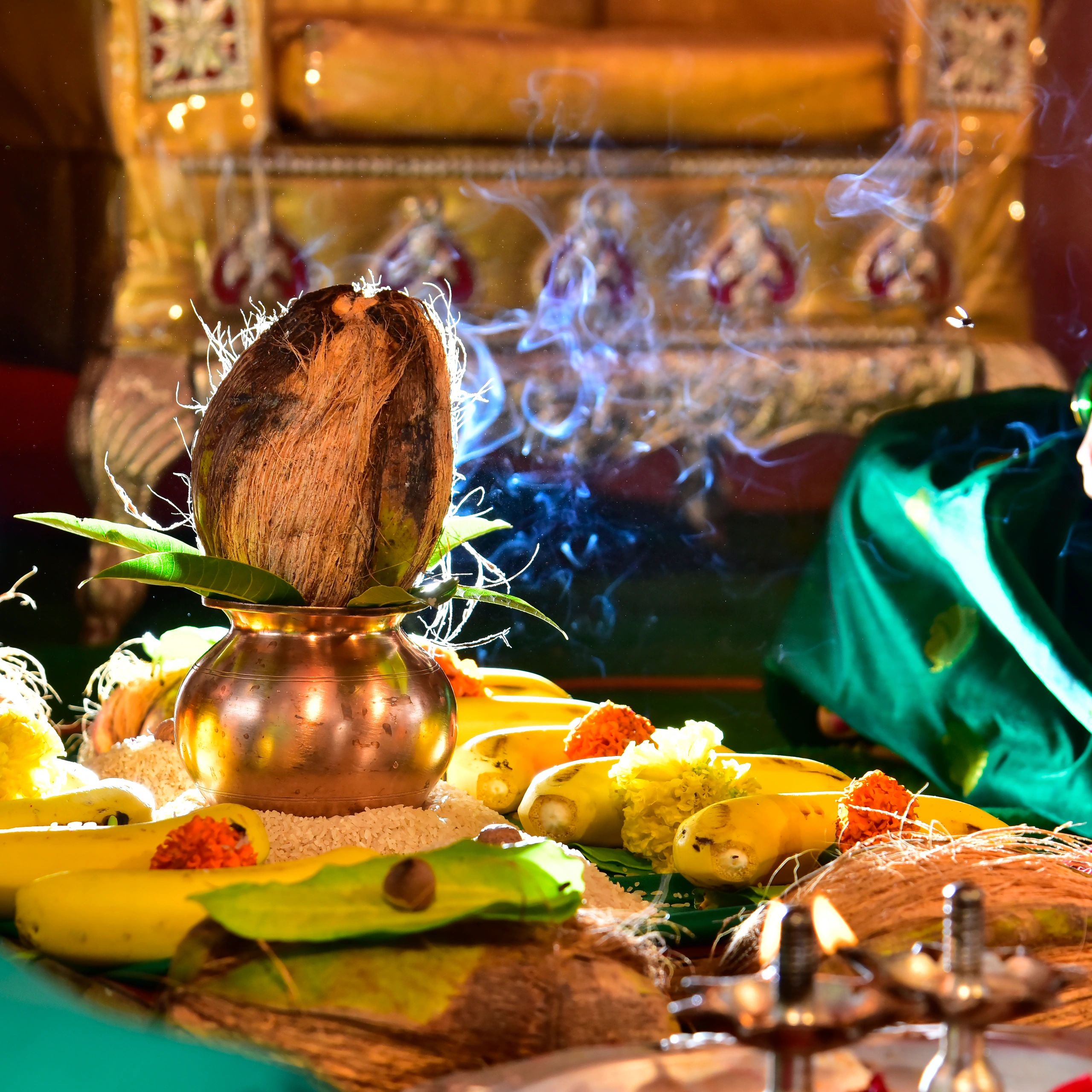 Traditional Indian pooja setup with coconut, bananas, flowers, and incense smoke.