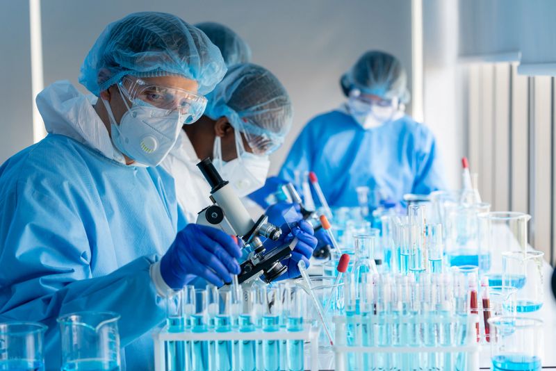 Caucasian Scientists use microscopes to research the covid-19 virus vaccine in a medical laboratory. Doctor uses biotechnology to research coronavirus in chemistry lab. Pharmaceutical science.