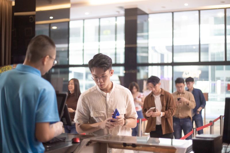 Asian Chinese man paying ticket with contactless payment mobile app at ticket counter.