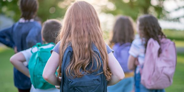 Group of kids with backpacks walking outside.