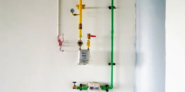 Colored pipes and a meter on a white wall.