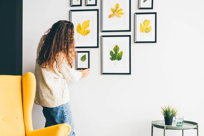 Woman hanging picture frame on wall in new house. Home decor ideas for autumn