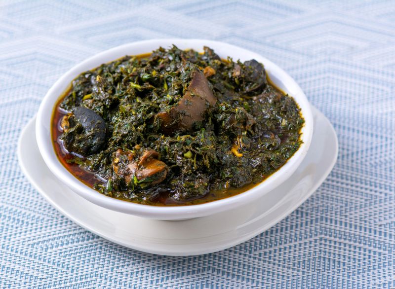 Close up shot of Efik tribe (Nigeria) Afang soup with beef and snails and prawns on a textured background