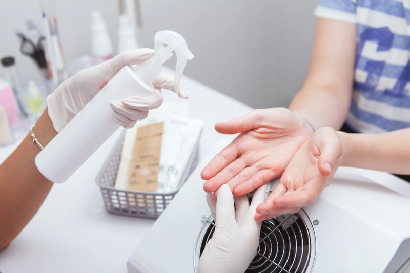 Unrecognizable female client having her hands disinfected before manicure at the salon