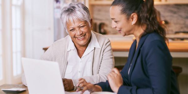 Two women happily working on a laptop together.