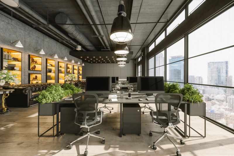 Interior of a modern luxurious open plan office space with dark gray furniture and city view.