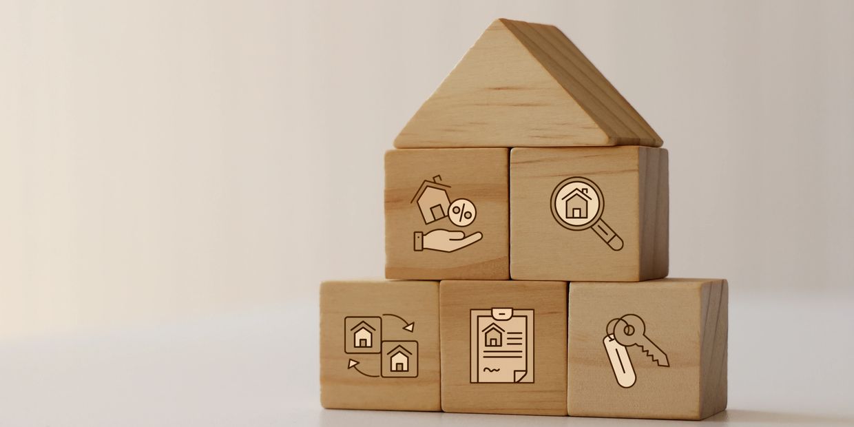 Wooden blocks arranged as a house with real estate icons.