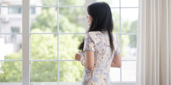 Woman standing and looking out of a window.