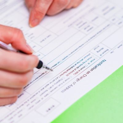 Person filling out a form with a pen.