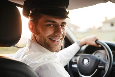 Smiling man in uniform driving a car.