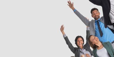 Happy business team celebrating success with raised hands and smiles.