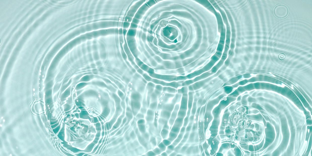 Ripples forming concentric circles on clear water surface.