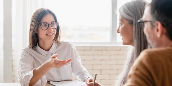 Young woman consulting older couple in bright office.