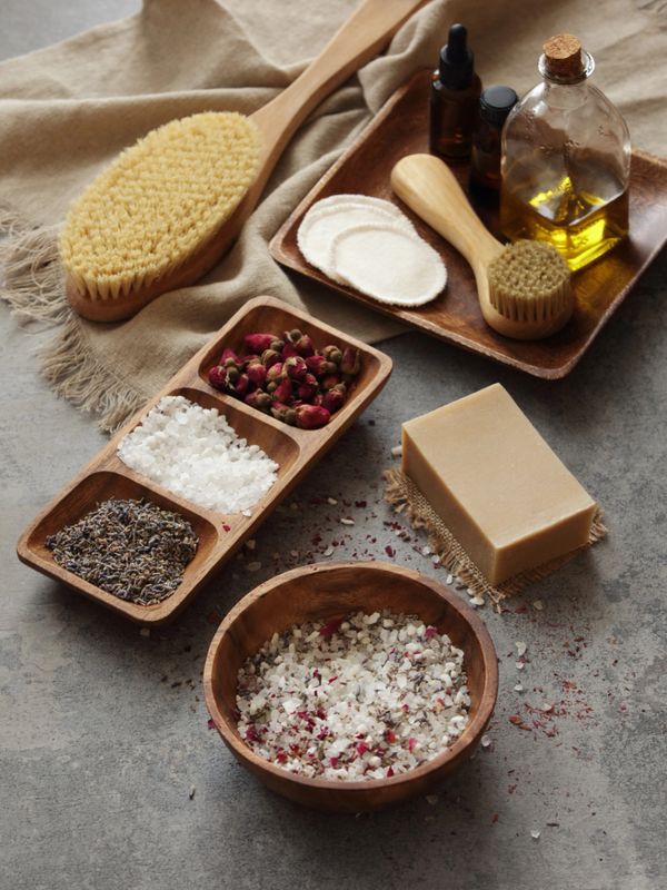 Natural spa essentials including brushes, oils, salts, and soap on a rustic surface.