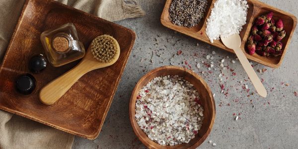 Assorted spices and salts displayed in wooden bowls and trays.