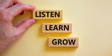 Someone placing blocks of wood saying, listen, learn, grow.