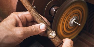 Close-up of hands polishing a ring with a rotary tool.