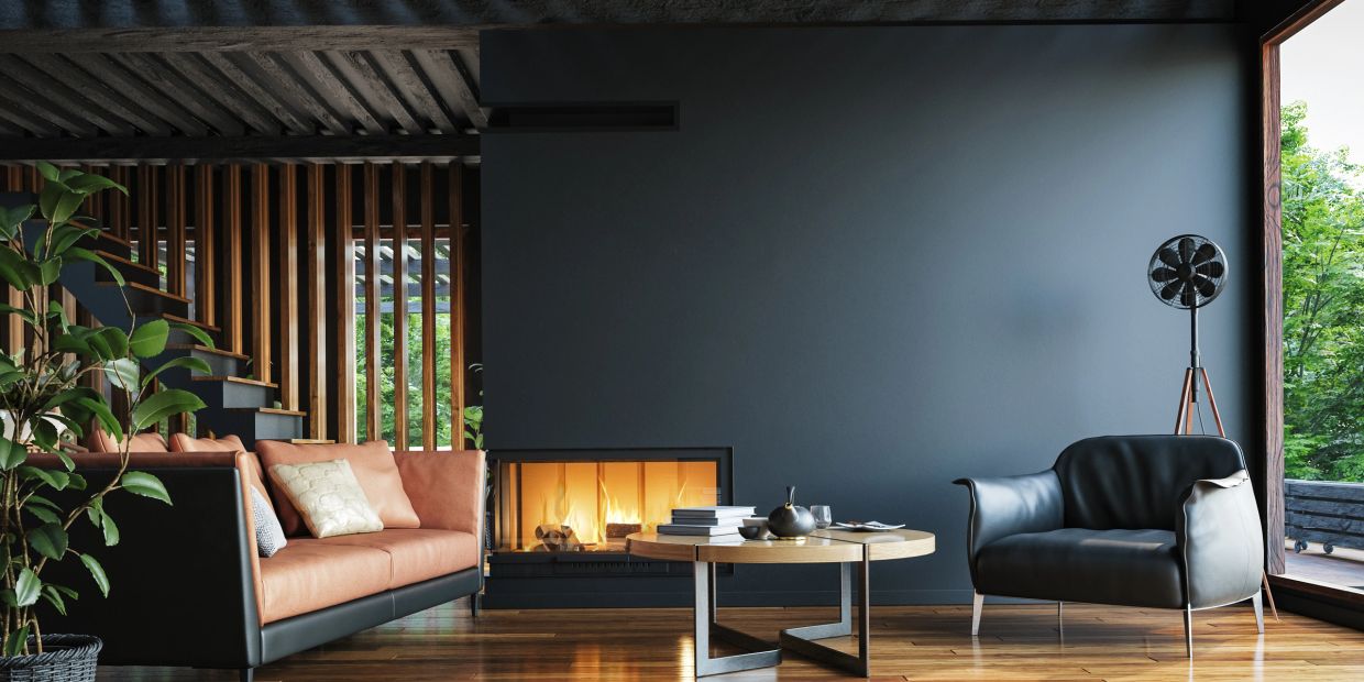 Modern living room with fireplace, leather sofa, armchair, and wooden decor.