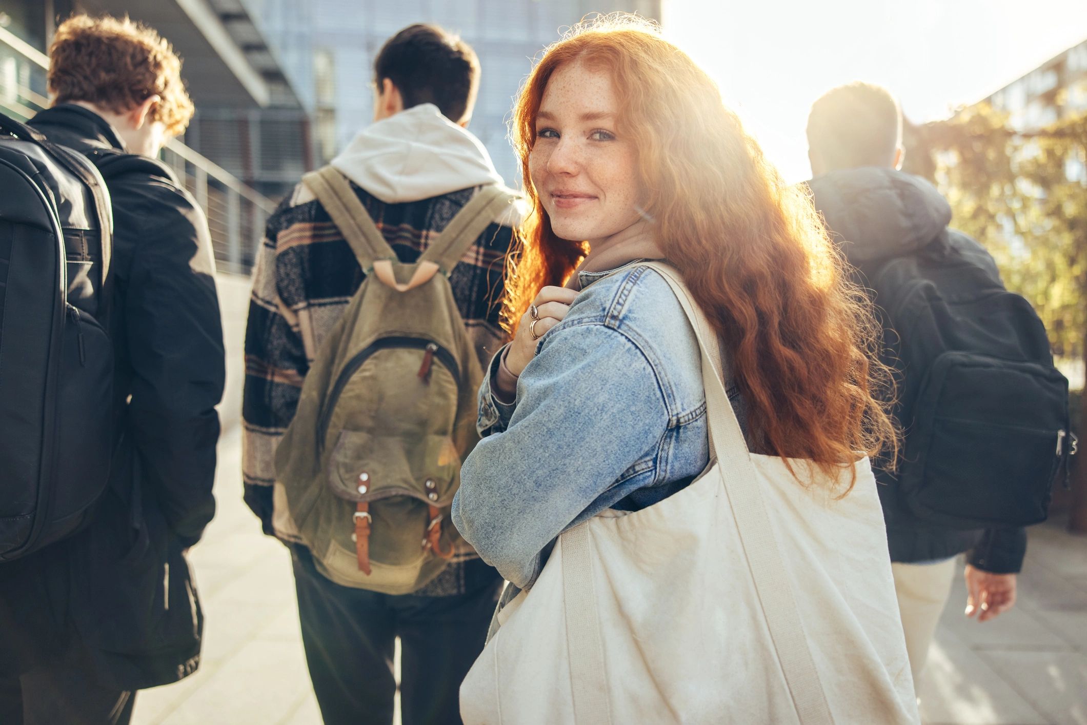 Smiling young woman with red hair walking with friends outdoors.
