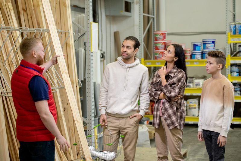 Sales manager of hardware store helping customers choose wooden planks