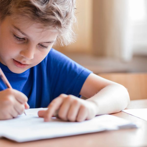 Young boy focused on writing in a notebook.