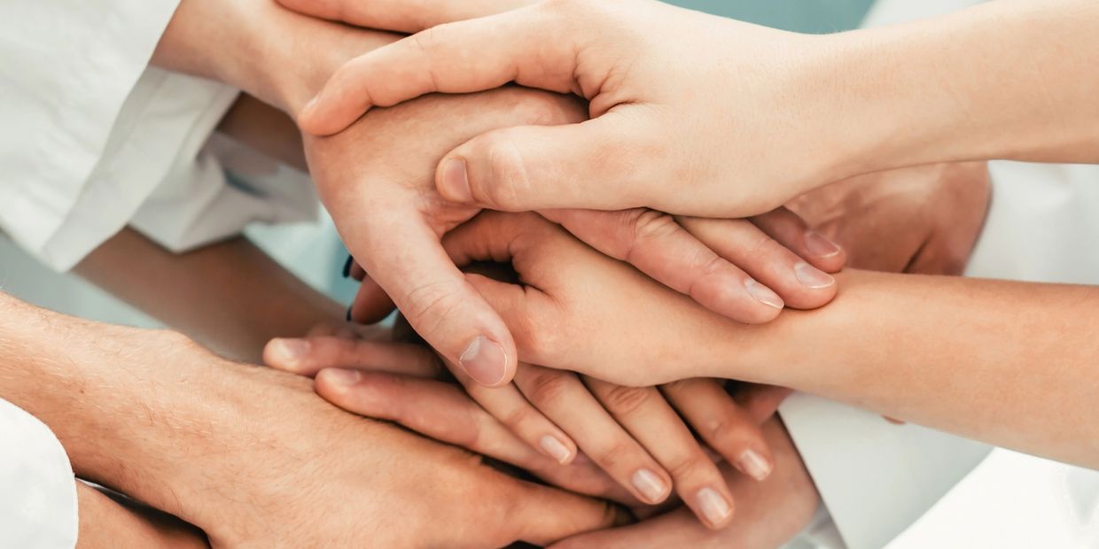 Multiple hands stacked together symbolizing teamwork and support.