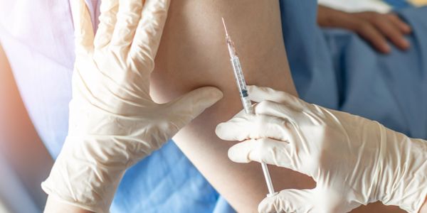 Healthcare worker administering a vaccine shot to a patient's arm.