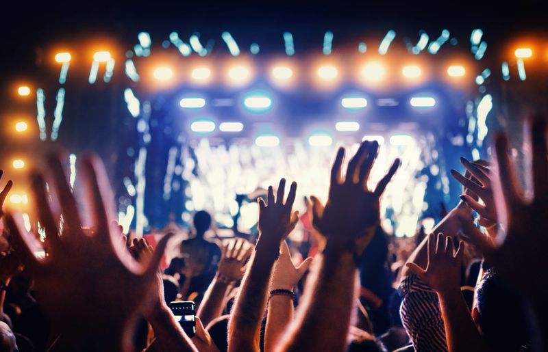 Crowd enjoying a live music concert with hands raised, vibrant lights and energetic atmosphere—highlighting nightlife, events, and global travel experiences.