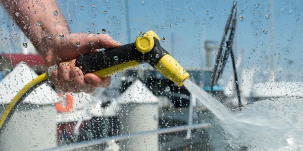 Hand spraying water with a hose nozzle.