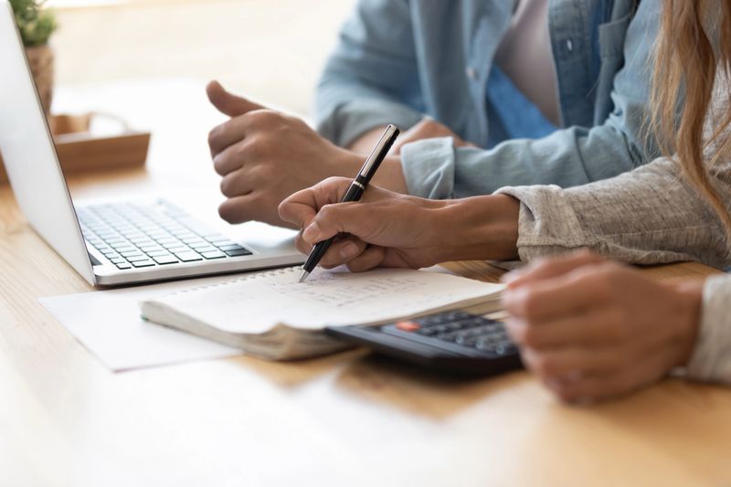 Close up spouses calculating family budget paying utility bills online using laptop, check loan payments, counting expenses. Economy, save money, finances management and planning, paperwork concept
