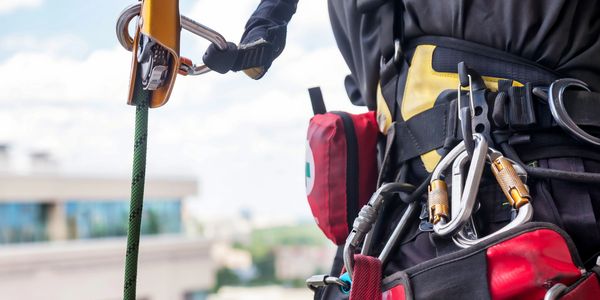 Climber using safety gear with carabiners and ropes.