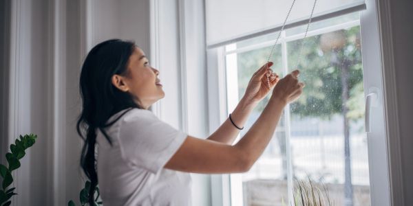 Woman adjusting window blinds.