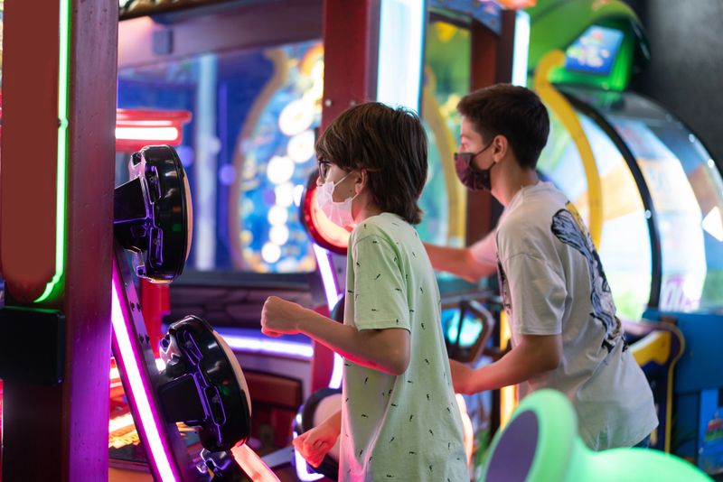 Happy young friends playing arcade game machine