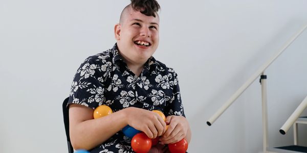 Smiling young man holding colorful balloons.