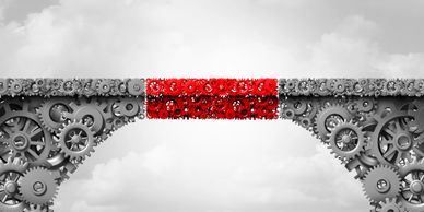 Image of a bridge constructed from gears, with the middle section colored bright red, suggesting a g