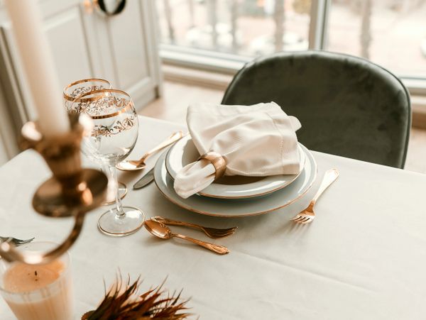 Elegant dining setting with gold-rimmed glassware and white napkin.