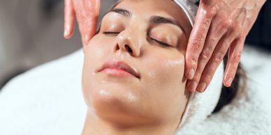 A beautiful brunette woman getting a facial rejuvenation massage.