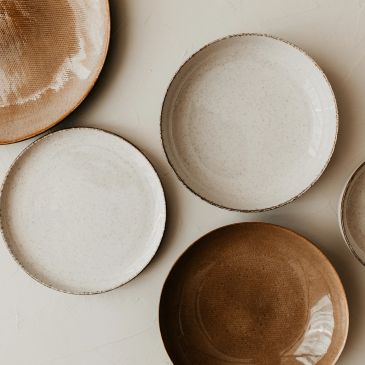 Assorted white and brown ceramic plates on a white surface.