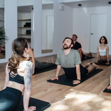 People practicing yoga in a bright studio, doing upward dog pose.