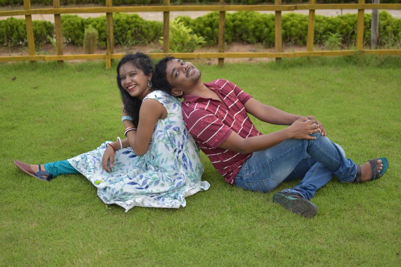 One Indian married couple sitting on the grass and enjoying their time together. concept of love and outing.