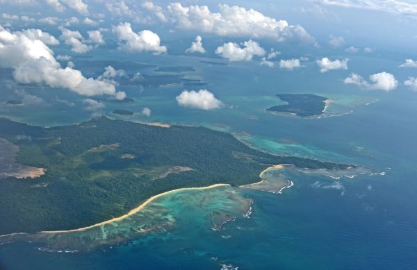Aerial view of lush islands with turquoise waters and scattered clouds.