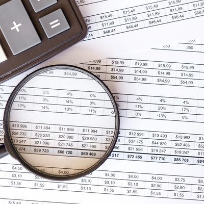 Lupa sobre documentos financieros con una calculadora.