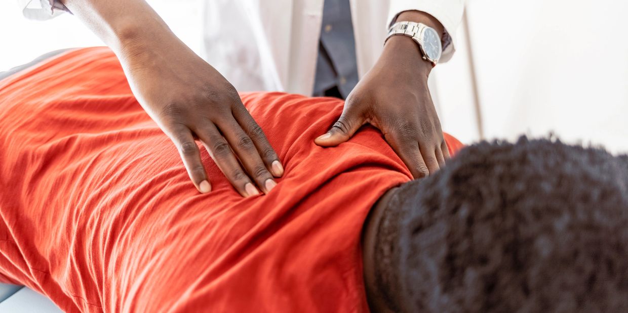 Therapist performing back massage on patient.
