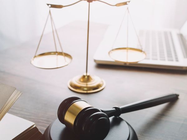 Judge's gavel and scales of justice on a desk with a laptop.