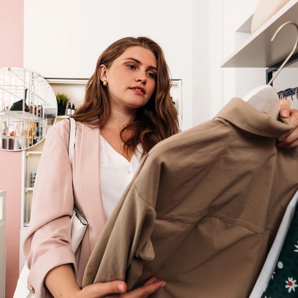 Woman examining a beige shirt in a stylish boutique.