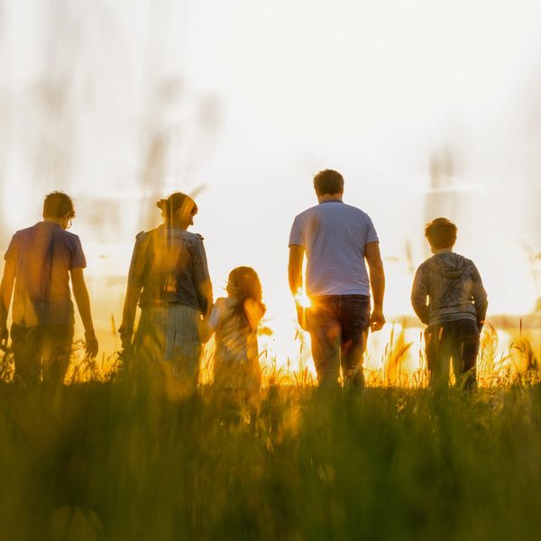 Family walking together at sunset in a field.