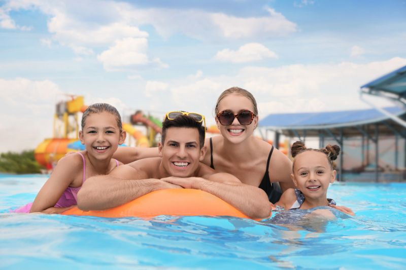 Happy family with inflatable ring in swimming pool at water park