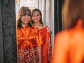 Two smiling women looking in a mirror.