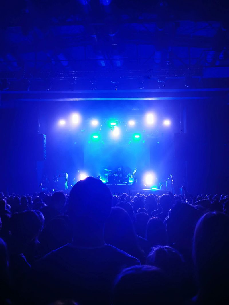 silhouettes of concert crowd in front of bright stage lights. Energy of music concert.